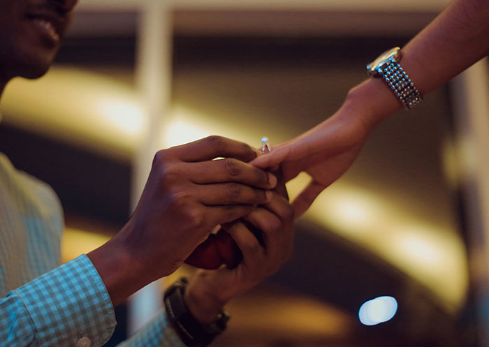 Man proposing with a ring to his partner, illustrating the ups and downs of having a partner who went from rags to riches.