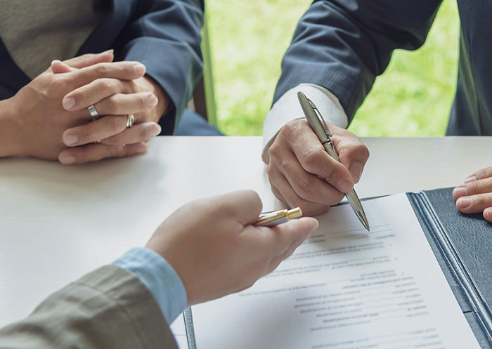 Couple discussing and signing documents representing the ups and downs of having a partner rise from rags to riches.