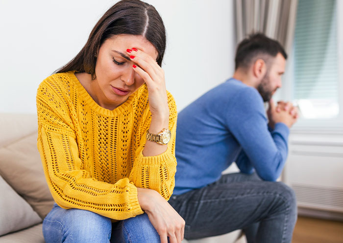 Ups and downs of having a partner who went from rags to riches shown by a stressed woman and distant man at home.