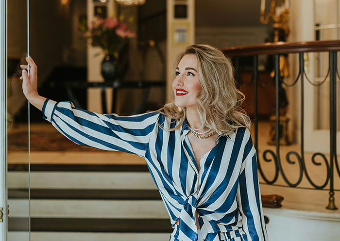 Woman in striped outfit smiling indoors, illustrating the ups and downs of having a partner who went from rags to riches.