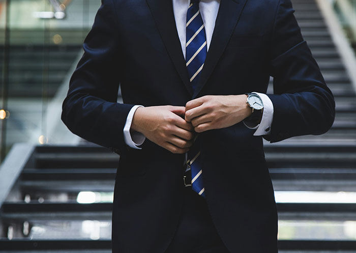 Man in a suit adjusting his jacket, symbolizing the ups and downs of having a partner who went from rags to riches.