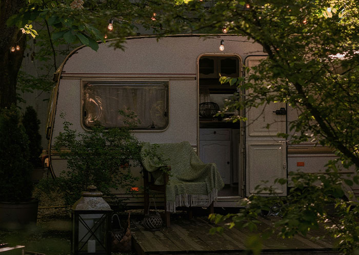 A cozy outdoor scene with a covered chair in front of a caravan, illustrating ups and downs of rags to riches.