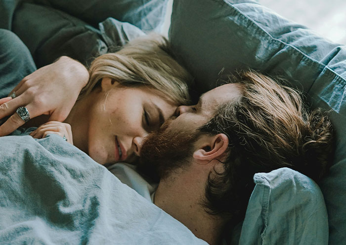 Couple cuddling in bed, sharing intimate moments reflecting the ups and downs of having a partner from rags to riches.