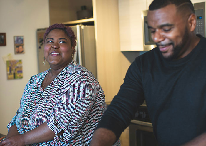Couple sharing a moment in their kitchen, highlighting the ups and downs of having a partner who went from rags to riches.