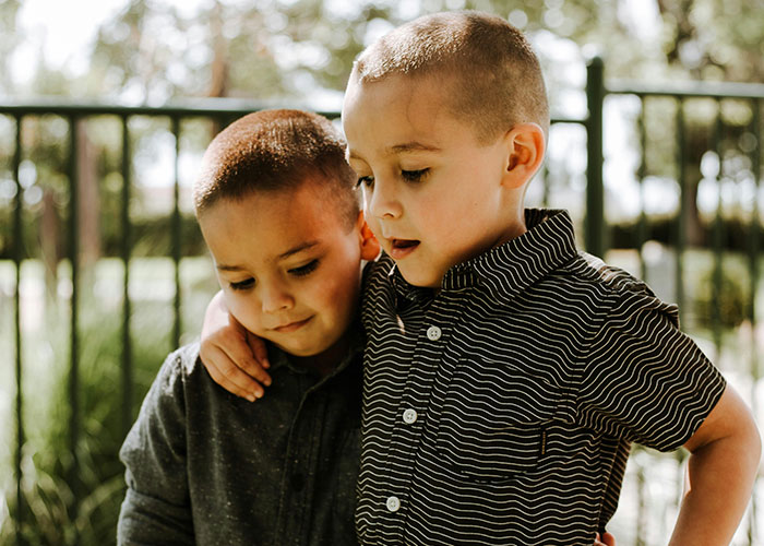 Two young boys outdoors, one comforting the other, illustrating the impact of horrible names on children’s lifelong pain.