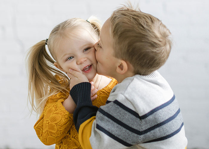 Two young children showing affection while representing the impact of horrible names on lifelong pain in families.