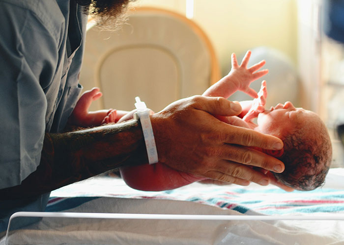 Adult holding newborn baby in a hospital setting, illustrating impact of horrible names on children’s lifelong pain and identity.