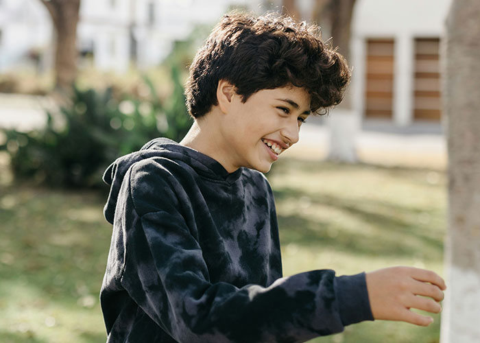 Smiling boy playing outdoors, illustrating the impact of jam Metallica and other horrible names on children’s lives.