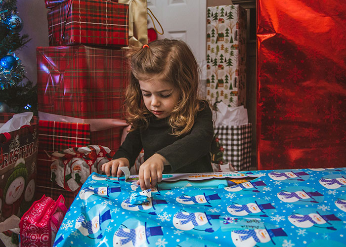 Young girl struggling with wrapped presents, illustrating emotional pain linked to unusual names causing lifelong issues.
