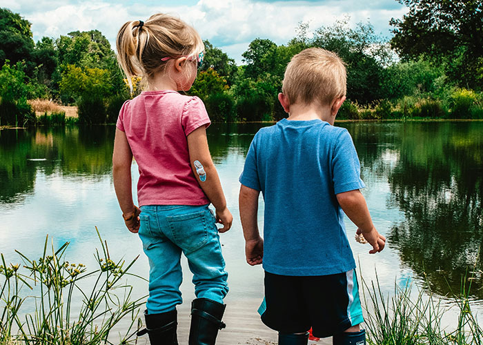 Two young children standing by a lake, illustrating themes of lifelong pain from horrible names given by parents.