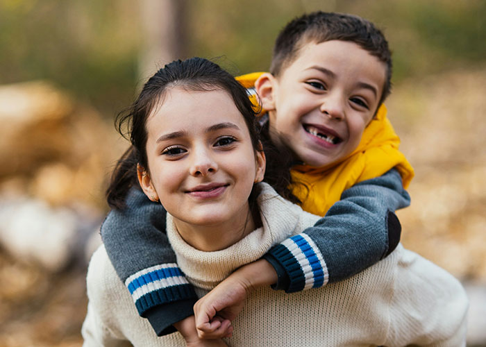 Two smiling children outdoors, depicting the impact of unusual names like Jam Metallica on lifelong experiences.