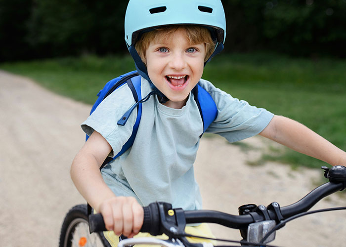 Young boy with helmet riding a bike outdoors, illustrating examples of horrible names that cause lifelong pain.