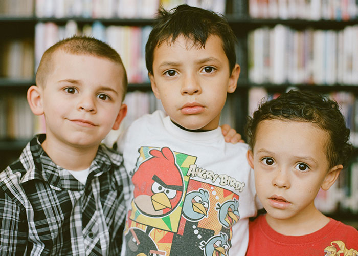 Three young boys standing close together indoors, illustrating challenges related to horrible names and lifelong pain.