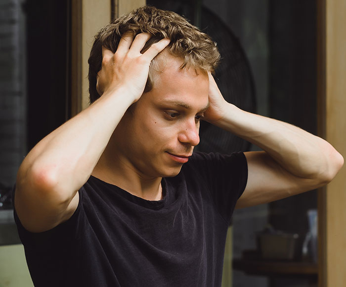 Young man looking distressed and holding his head inside a room, reflecting on places people visited that gave off creepy vibes.