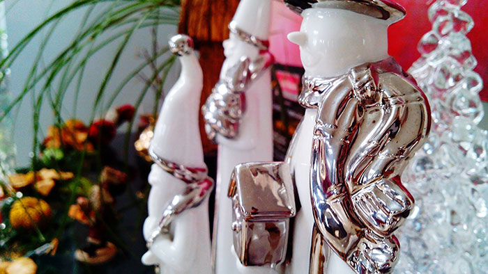 White and silver snowman figurines surrounded by decorative plants creating creepy vibes atmosphere.