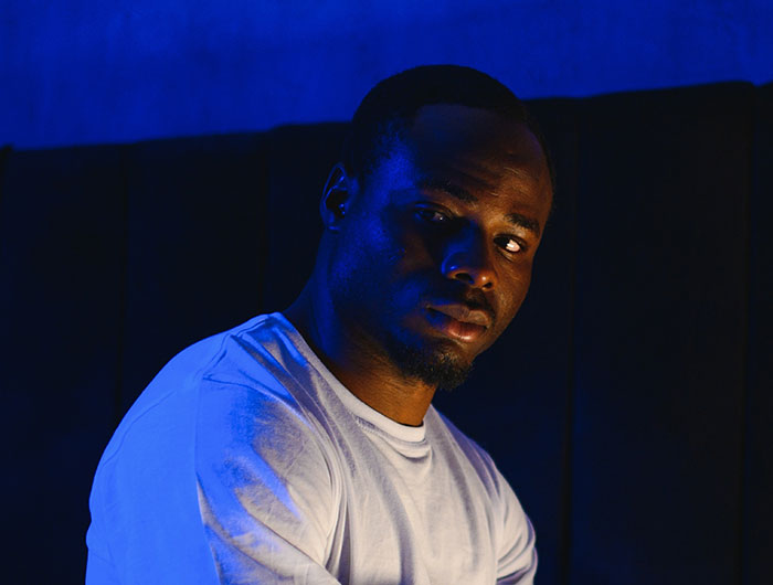 Man in white shirt illuminated by blue light, evoking creepy vibes in a dark, gloomy setting.