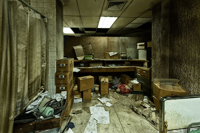 Abandoned room filled with old boxes and scattered papers, evoking creepy vibes in a neglected place.