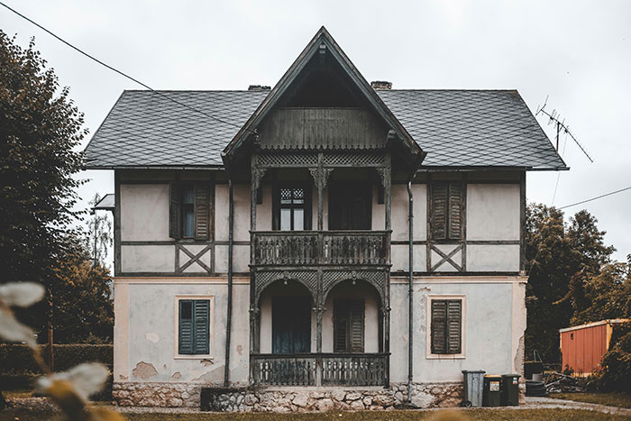 Old abandoned house with boarded windows and weathered walls, evoking creepy vibes in a secluded area.