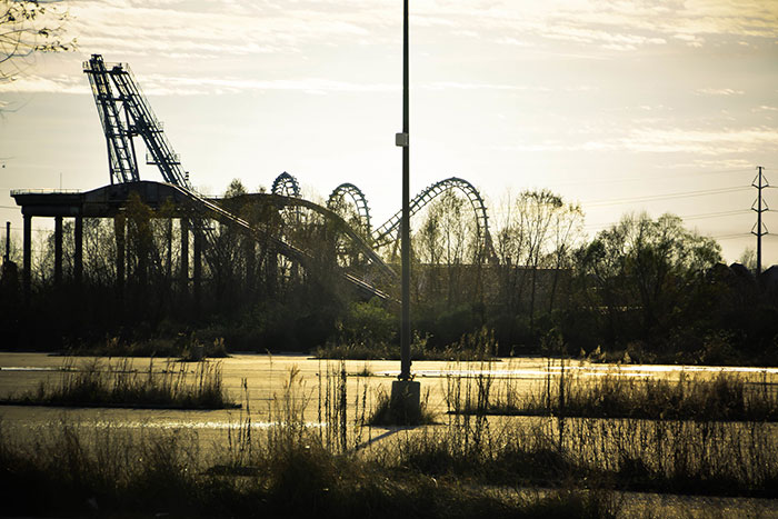 Abandoned roller coaster in a desolate, overgrown area capturing creepy vibes of eerie, forgotten places people visited.