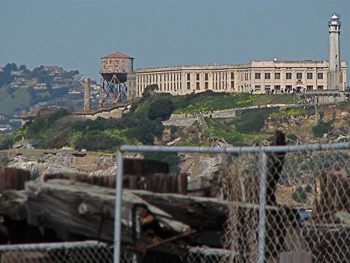 View of a historic prison and lighthouse on an island, one of the places people visited with creepy vibes.