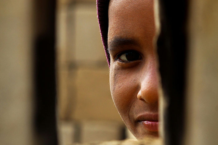 Close-up of a person's face peeking outdoors through a narrow gap, evoking creepy and unsettling outdoor moments.