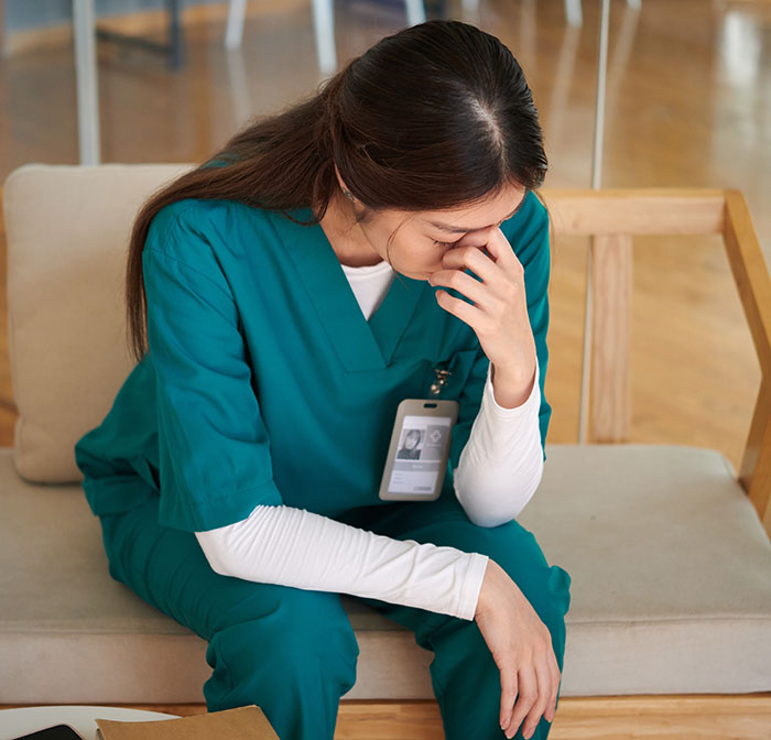 Stressed healthcare worker in scrubs sitting on a bench, reflecting on the creepiest parts of their job.