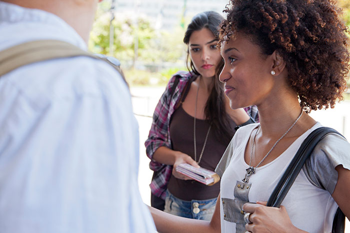 Three young women having a serious conversation outdoors, illustrating workers revealing the creepiest parts of their jobs.