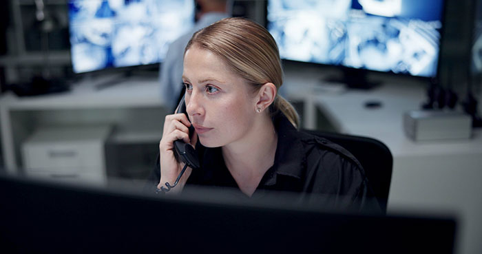 Security worker on phone monitoring multiple screens, illustrating the creepiest parts of their job experience.