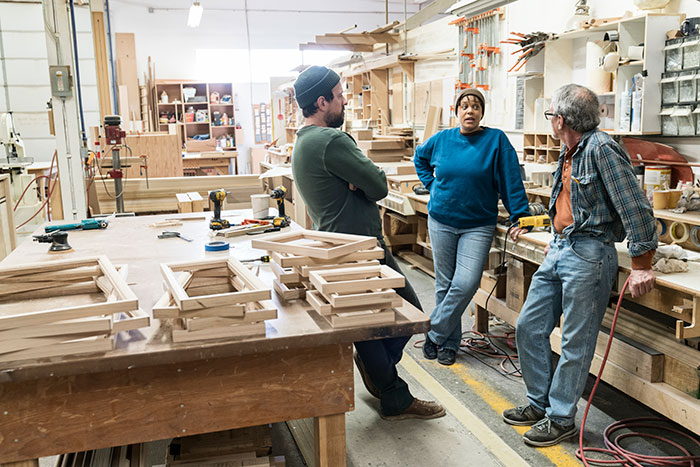 Three workers discussing safety concerns in a woodworking shop amid the creepiest parts of their jobs.