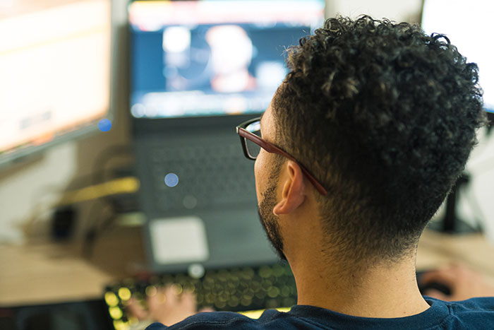 Man with glasses working on a laptop, illustrating workers revealing the creepiest parts of their jobs.