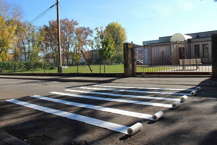 Street art photo showing creative white stripes made from paper rolls on a street, blending art with urban space.