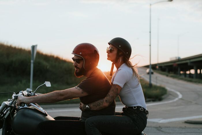 Man and woman wearing helmets riding a motorcycle at sunset, illustrating risks to avoid for autopsy techs table safety. - 5