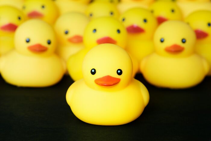 Yellow rubber ducks arranged closely together on a black surface, symbolizing heartwarming harmless secrets.