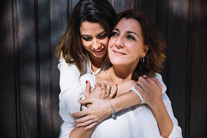 Mother and daughter embracing outdoors, reflecting on stepdad suggesting punishing kid for using native language.