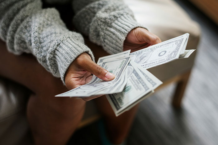 Woman counting cash at home, illustrating refusal to go on Christmas gift trip without paying for flight.