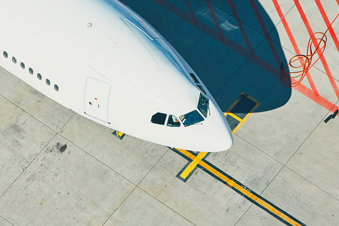 Close-up of a white airplane nose parked on a tarmac with yellow and red markings visible on the ground.