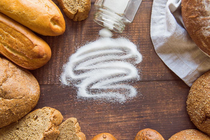 Various types of bread surrounding spilled salt on a wooden surface representing safe things people can’t stop freaking out about.