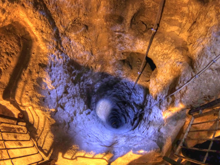 Deep, mysterious underground city shaft with textured walls, highlighting 18 stories and 280 feet depth discovery.
