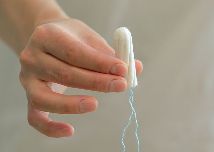 Hand holding a tampon representing disgusting things people discovered about their friends that made them rethink relationships.