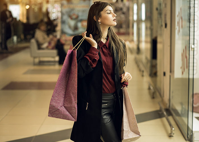 Woman in a shopping mall holding bags, reflecting on disgusting things discovered about friends that made her rethink the relationship.
