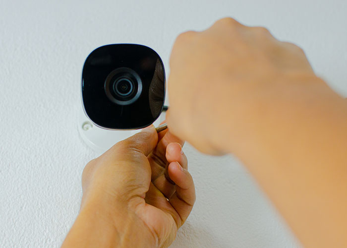 Close-up of hands installing a security camera on a wall representing people discovering disgusting things about their friends.