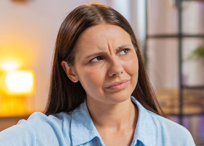 Woman with long brown hair wearing a blue shirt looking confused and disgusted, reflecting on friendship discoveries.
