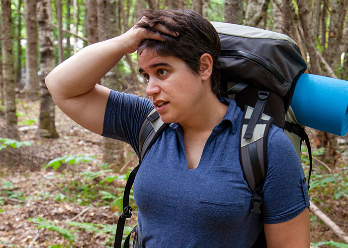 Person with backpack in forest looking stressed, reflecting on disgusting things discovered about their friends and relationships.
