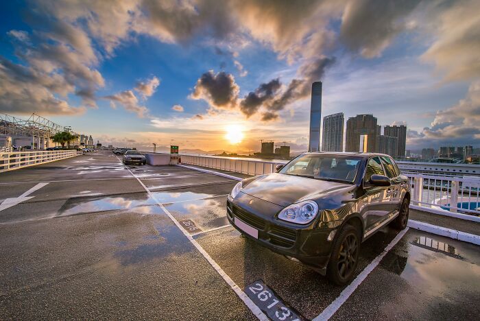 Black luxury SUV parked on a rooftop with city skyline at sunset, illustrating people who found out something disgusting about a friend.