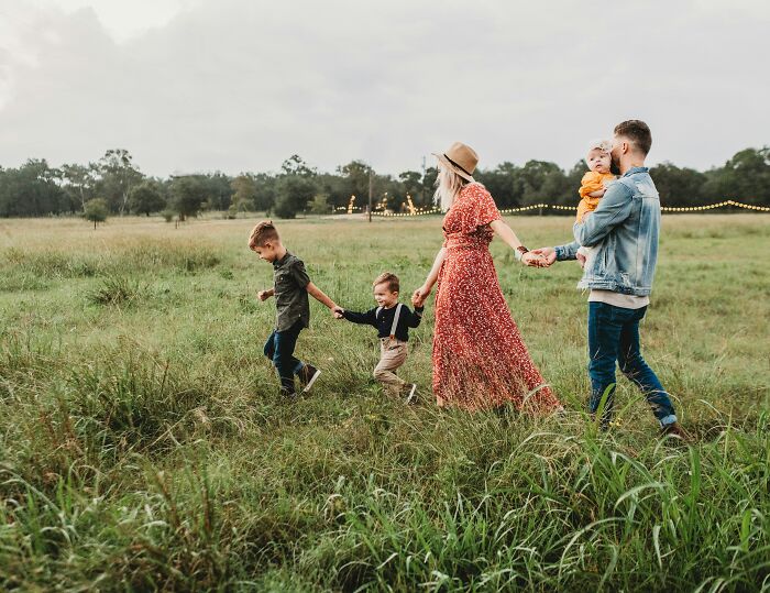 Family walking hand in hand through a grassy field, illustrating trust broken by disgusting friend revelations.