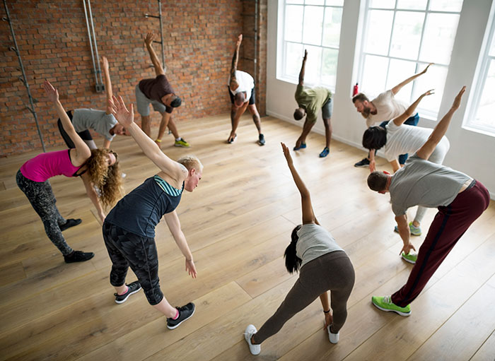 Group of people stretching in a fitness class, illustrating a guy at his breaking point with clumsy girlfriend theme.