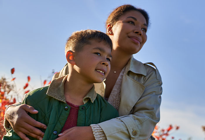Mother embracing her son outdoors on a sunny day, symbolizing family bonds amid divorce and truth revelations.