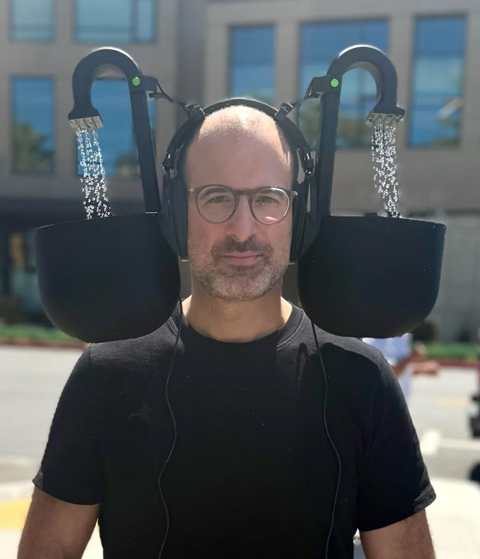 Man wearing headphones with two large buckets attached, each pouring water, a DIY disaster mistake outdoors.