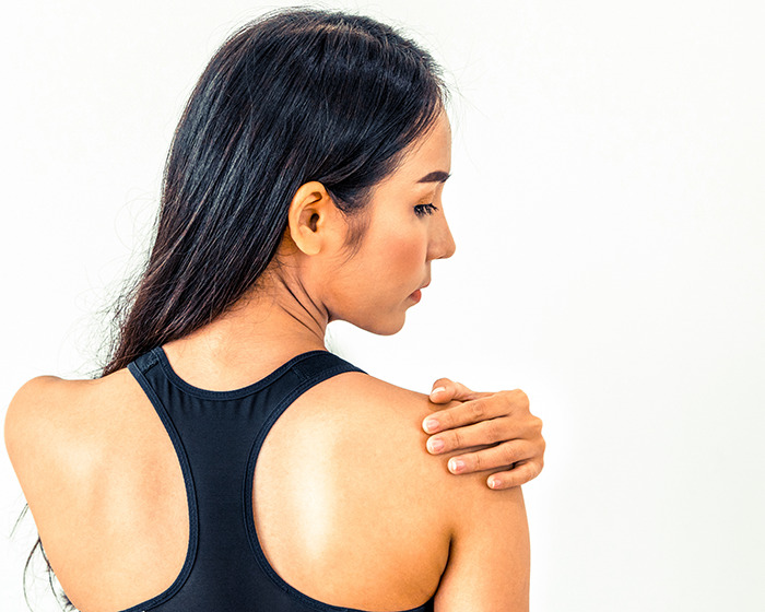 Woman in black sportswear touching shoulder, illustrating the doctor reveals 11 push-ups challenge for women&rsquo;s health.