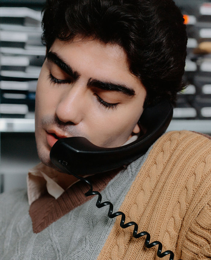 Man talking on a corded phone, dealing with calls meant for a doctor, starting to book appointments instead.